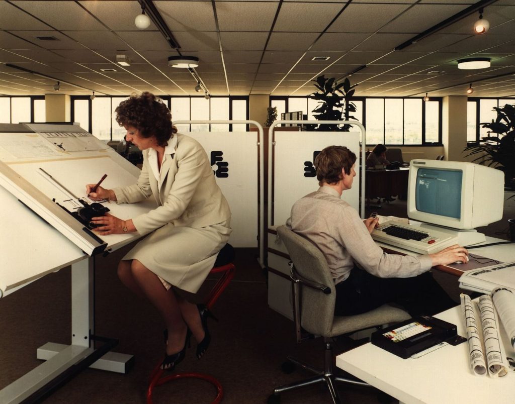 AI Agents Move From Demos to Daily Workplace Tools Office staff working with laptops in a bright meeting room
